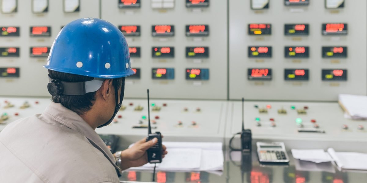 workers using walkie-talkie in control room of a factory.